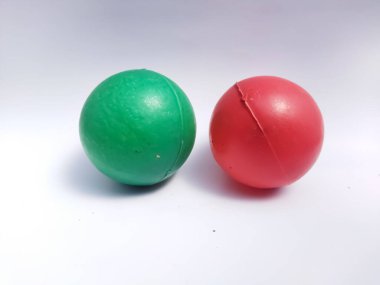 A couple of small, green and red plastic balls with a white background