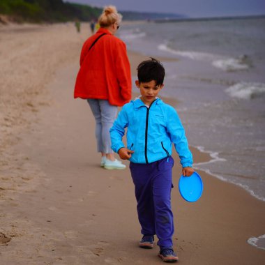 A beautiful shot of a child wearing a blue shirt at a beach on a rainy day