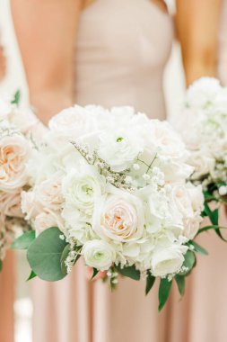 A vertical closeup of bridesmaids holding bouquets of roses