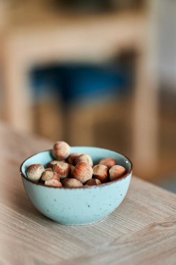 Arka planda bulanık bir sehpanın üzerindeki fındık kasesinin dikey görüntüsü.