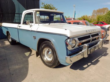 White and sky blue old Chrysler Dodge D 200 pickup truck late 1960s in a warehouse yard. Utility or farming tool. Expo Fierro 2022 classic car show.