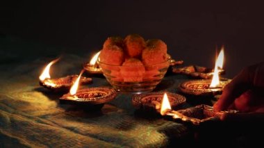 Diwali Diya oil lamps are placed on a table among other glowing Diya lamps. Decorative Diya lamps.