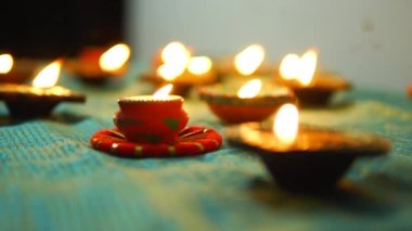 Diwali Diya oil lamps are placed on a table among other glowing Diya lamps. Decorative Diya lamps.