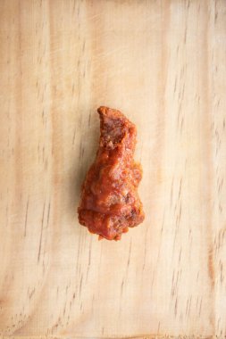 A vertical shot of a piece of fried buffalo wing on a wooden surface