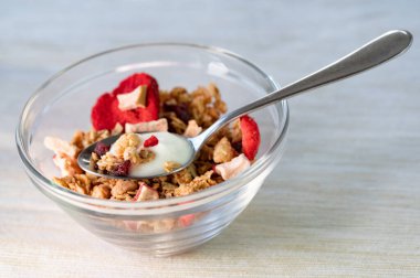 A closeup of the glass bowl with strawberries and nuts on the table. Granola.