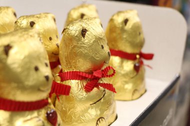 A close-up shot of chocolate bears wrapped with golden paper and red tie for Christmas