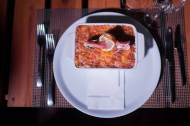 Masadaki parlak tencerede deniz ürünleri lazanyası.