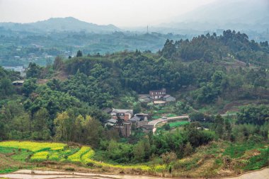 Arkasında yeşil dağlar olan uçsuz bucaksız bir tarım arazisinin güzel bir manzarası.