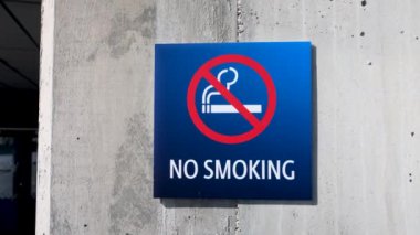 A closeup of a blue No Smoking sign on the wall