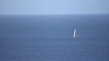 A bird's eye view of a boat sailing in a blue seascape on a sunny day