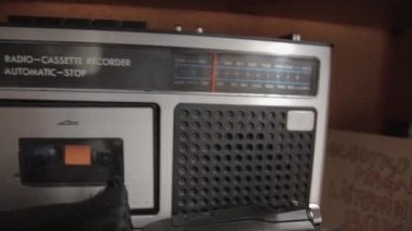 A closeup shot of a vintage radio cassette recorder and vintage camera Agfa box on a wooden shelf with blurred background