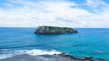 An aerial view of an islet near a shore on a cloudy day