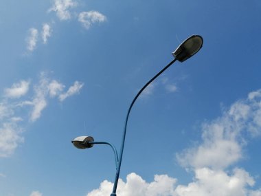 A low angle shot of metallic lantern posts against a cloudy blue sky