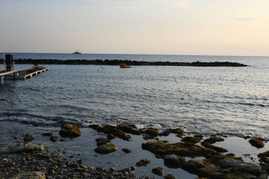 A beautiful view of rocks in the water under cloudy sky in the time of sunset
