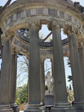 A vertical shot of the columns and statue in the Parque de el Capricho in Madrid, Spain