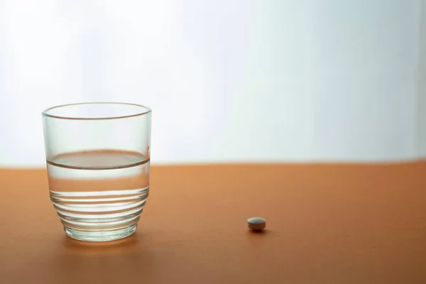 a closeup shot of a pill with a cup of water