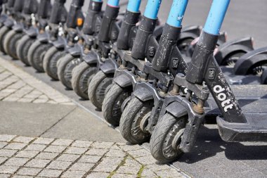 A closeup shot of a row of electric rental scooters parked in the street