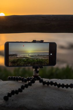 Akıllı telefon, deniz üzerinde gün batımının bir zaman çizelgesini çeker.