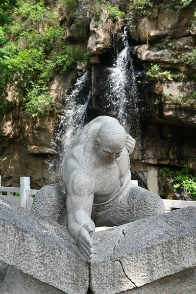 A vertical shot of a sculpture of a man breaking stones in a park