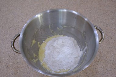 A top view of a bowl with whipped mixture and flour