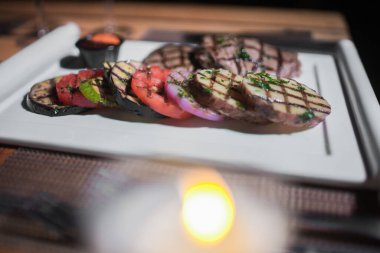 Kızarmış patates, domates ve soğanlı bir tabak et.