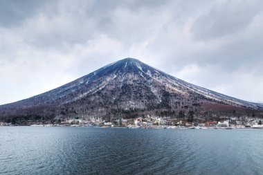 View to Mt. Nantai over the Chuzenji Lake on a cloudy winter day with snow near Nikko, Japan.