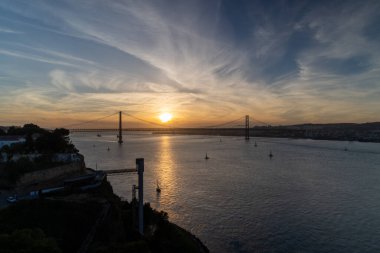 A beautiful view of the bridge over the river in Lisbon, Portugal at orange sunset