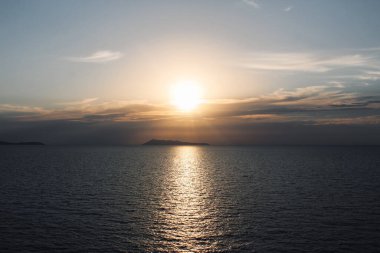 The golden light of the sun through the clouds illuminates the seashore