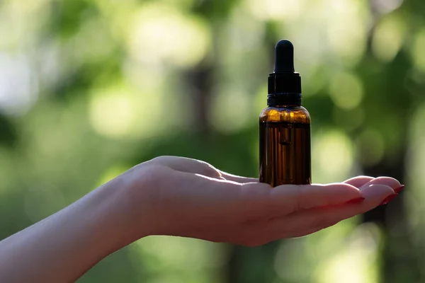Hand showing essential oil bottle. Woman hand holding essential oil, bottle. Copy space.