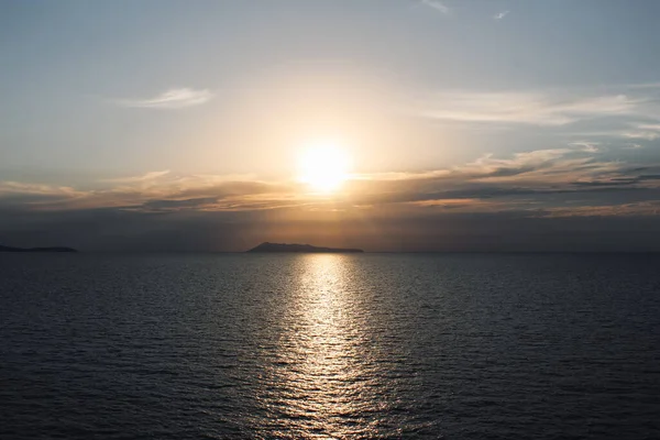 The golden light of the sun through the clouds illuminates the seashore