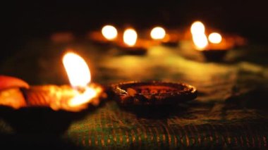 Diwali Diya oil lamps are placed on a table among other glowing Diya lamps. Decorative Diya lamps.
