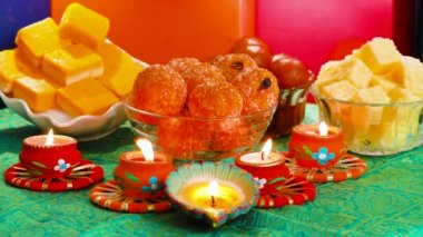 Colorful Diwali oil lamps, Deepavali oil lamps lighted in beautiful formation with bowls full of different Diwali sweets . Decorative Colorful Diya