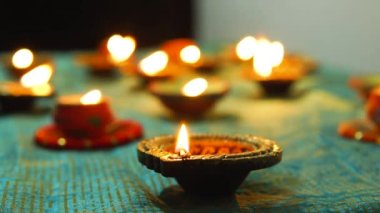 Diwali Diya oil lamps are placed on a table among other glowing Diya lamps. Decorative Diya lamps.