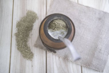 A top view shot of a spice inside a ceramic pot on a grunge white wooden surface