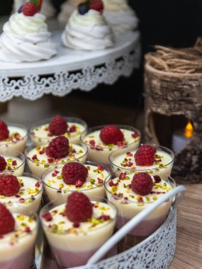 A 3 color puding in small glasses with raspberry on the top