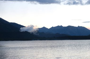 The beautiful mountains colored by the sunset with a calm lake in the front