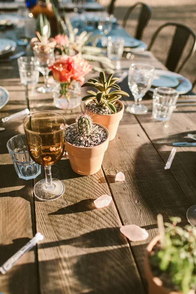 A vertical shot of a modern outdoor event table setting in the desert with small cactus plants on the table