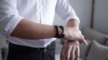 A closeup of a male arranging his bracelet accessories around his wrist