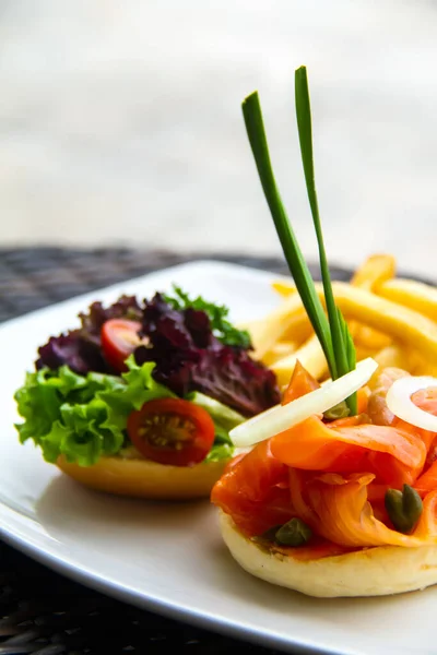 Piękne Ujęcie Hamburgera Łososia Sałaty Pomidora Frytek Białym Talerzu — Zdjęcie stockowe