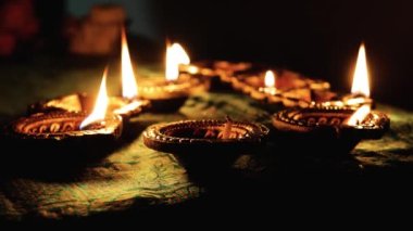 Diwali Diya oil lamps are placed on a table among other glowing Diya lamps. Decorative Diya lamps.