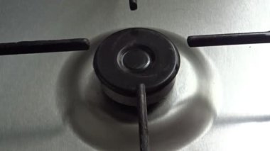 A closeup shot of a man lighting a gas stove with a gas lighter gun