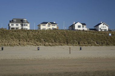 27 Mart 2022, Zandvoort, Kuzey Hollanda, Hollanda, alacakaranlıkta kum tepelerinde beyaz evler (yatay))