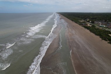 An aerial view of the soft ocean waves with foam on a sandy beach