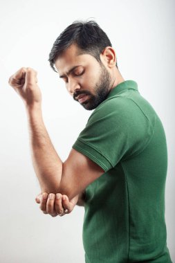Young Indian guy clutching his elbow injury with pain isolated in white background.