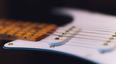 Elektro gitarın tellerindeki detayların yakın plan çekimi.