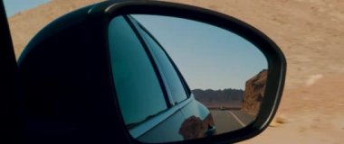 The reflection of a road in the side mirror of a moving car