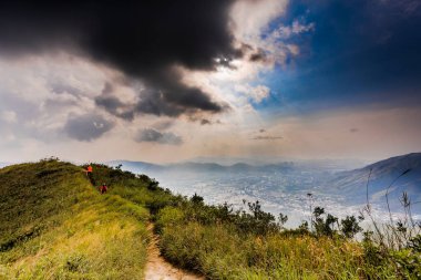 View of a natural landscape narrow path on a mountain peak with grass, and mountain scape in the background
