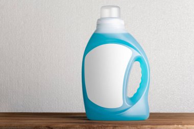 A liquid detergent bottle with blank label on a wooden board