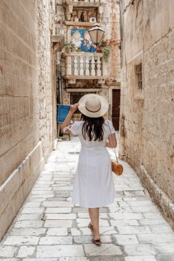 A rear view of a young woman in a picturesque narrow street in Trogir, Croatia