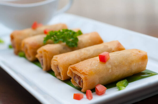 A closeup shot of fried Chinese spring rolls with sweet chili sauce